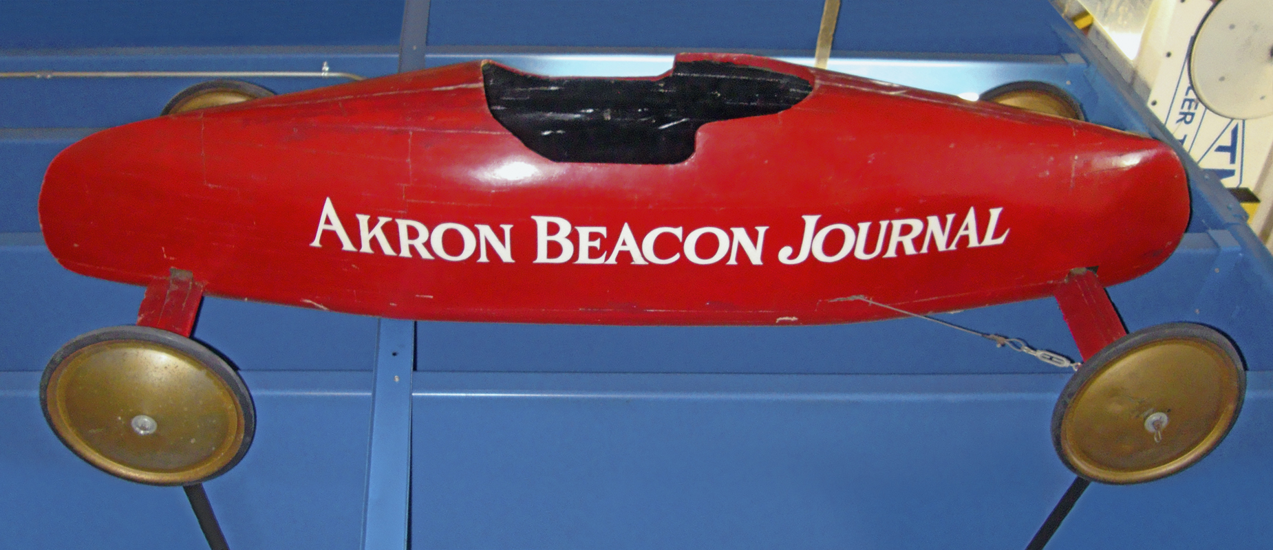 Side view of Donald Strub's red enclosed 1948 All-American championship Soap Box Derby car with gold wheels